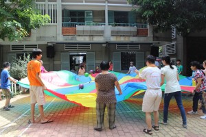 Adults and children playing outside with a parachute